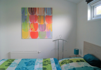 Dormitorio luminoso en Chalet Marron con arte colorido en la pared, cama moderna y ventana en Alemania.