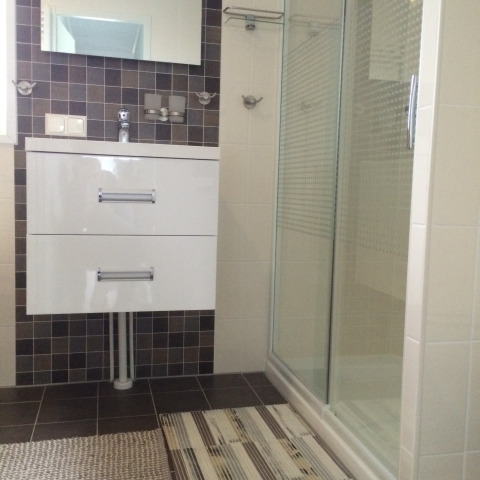 Moderne badkamer met douche, spiegel en wit meubel in Chalet Marron, Camping & Ferienpark Brilon, Duitsland.