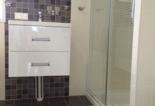 Baño moderno con ducha, espejo y mueble blanco en Chalet Marron, Camping & Ferienpark Brilon, Alemania.