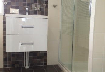 Baño moderno con ducha, espejo y mueble blanco en Chalet Marron, Camping & Ferienpark Brilon, Alemania.