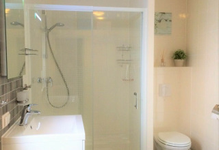 Baño moderno con ducha, inodoro y lavabo en Chalet Marron del Camping & Ferienpark Brilon, Alemania.