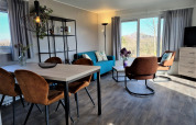 Salón moderno en Chalet Brilon con grandes ventanales, sillones marrones y magníficas vistas al exterior.