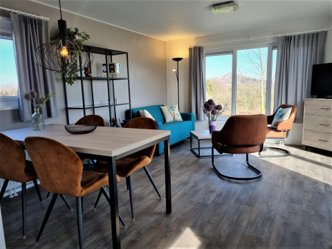 Salón moderno en Chalet Brilon con grandes ventanales, sillones marrones y magníficas vistas al exterior.