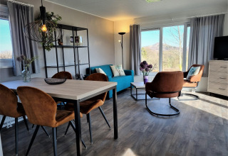 Salón moderno en Chalet Brilon con grandes ventanales, sillones marrones y magníficas vistas al exterior.