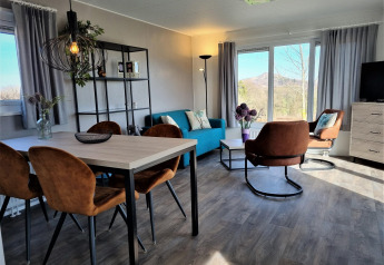 Modern living room at Chalet Brilon with large windows, brown chairs, blue sofa, and scenic view.