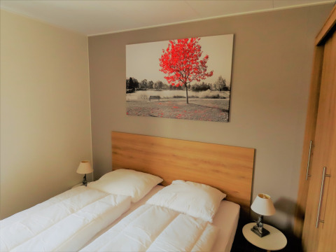 Dormitorio en Chalet Brilon con dos camas individuales, arte moderno en la pared y luz cálida en Alemania.