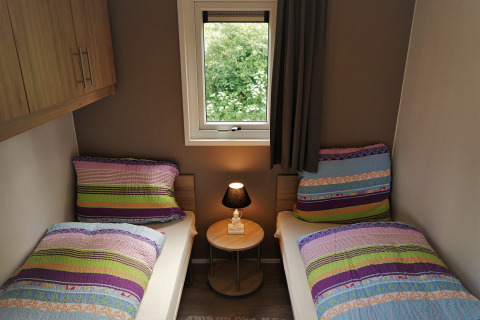 Dos camas individuales con ropa de cama colorida en una acogedora habitación en Chalet Brilon, Camping & Ferienpark Brilon, Alemania.