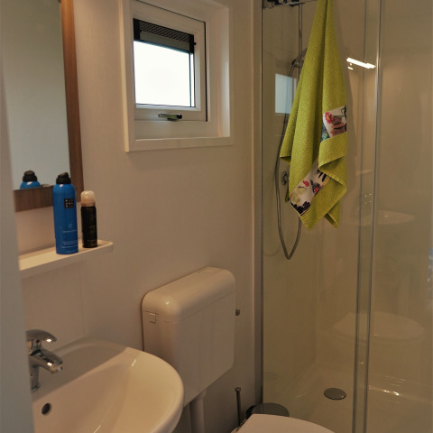 Baño moderno con ducha, lavabo, inodoro y toalla verde colgada en Chalet Brilon, Alemania.