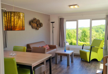 Sala de estar en Chalet Brilon en Camping & Ferienpark Brilon, Alemania, con muebles modernos y vista verde.