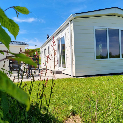Chalet de lujo luminoso con grandes ventanales en Camping & Ferienpark Brilon, rodeado de césped verde.