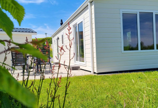 Chalet de lujo luminoso con grandes ventanales en Camping & Ferienpark Brilon, rodeado de césped verde.