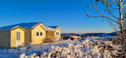 Casa mobile gialla Chalet Limonet innevata al Camping & Ferienpark Brilon, Germania, sotto cielo azzurro.