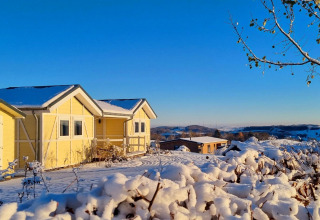 Casa móvil amarilla Chalet Limonet nevada en Camping & Ferienpark Brilon, Alemania, bajo un cielo azul claro.