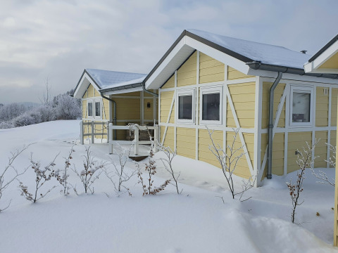 Casa móvil amarilla Chalet Limonet cubierta de nieve en Camping & Ferienpark Brilon, Alemania, en invierno.