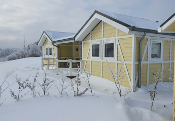 Casa móvil amarilla Chalet Limonet cubierta de nieve en Camping & Ferienpark Brilon, Alemania, en invierno.