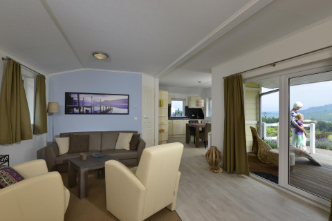 Sala de estar y cocina en Chalet Limonet, Camping & Ferienpark Brilon, Alemania, con vista a la terraza.