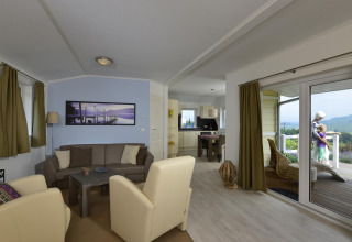 Sala de estar y cocina en Chalet Limonet, Camping & Ferienpark Brilon, Alemania, con vista a la terraza.