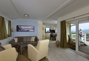 Sala de estar y cocina en Chalet Limonet, Camping & Ferienpark Brilon, Alemania, con vista a la terraza.