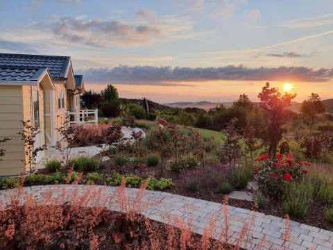 Casa móvil Chalet Limonet en Camping & Ferienpark Brilon, Alemania, con jardín y puesta de sol al fondo.