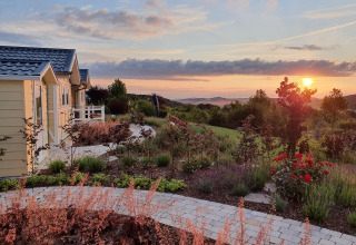Casa móvil Chalet Limonet en Camping & Ferienpark Brilon, Alemania, con jardín y puesta de sol al fondo.