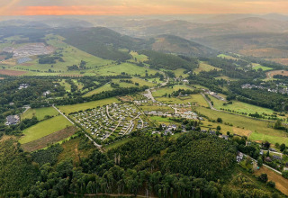 Vista aérea de Chalet Limonet en Camping & Ferienpark Brilon, Alemania, rodeado de colinas verdes y naturaleza.