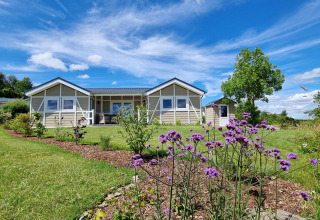 Vista del mobil home Chalet Limonet y jardín en Camping & Ferienpark Brilon bajo cielo azul brillante en Alemania.