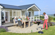 Cuatro adultos disfrutan de una barbacoa en la cabaña Calcelux, Camping & Ferienpark Brilon, Alemania.