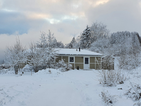 Escena invernal de la cabaña Calcelux cubierta de nieve en Camping & Ferienpark Brilon, Alemania.