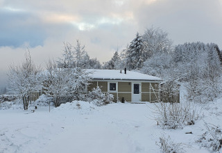 Escena invernal de la cabaña Calcelux cubierta de nieve en Camping & Ferienpark Brilon, Alemania.