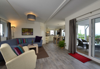 Lichte woonkamer in de Calcelux-cabine bij Camping & Ferienpark Brilon met open keuken en terraszicht.