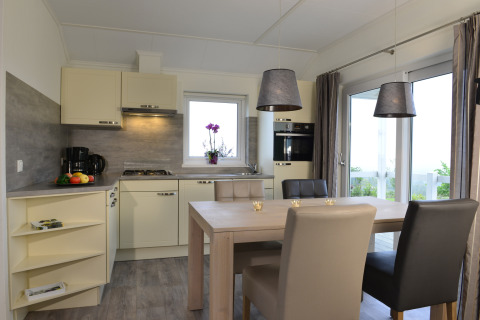 Cocina y comedor modernos en la cabaña Calcelux de Camping & Ferienpark Brilon, Alemania, con grandes ventanales.