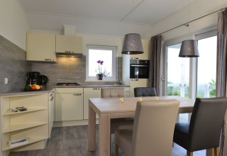 Cocina y comedor modernos en la cabaña Calcelux de Camping & Ferienpark Brilon, Alemania, con grandes ventanales.