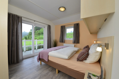 Dormitorio moderno y luminoso con cama doble y vistas al jardín en la cabaña Calcelux de Brilon, Alemania.