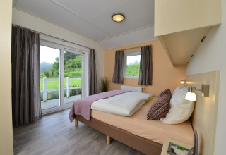 Dormitorio moderno y luminoso con cama doble y vistas al jardín en la cabaña Calcelux de Brilon, Alemania.