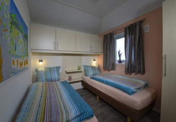 Twee eenpersoonsbedden met kleurrijke strepen in een gezellige kamer van Calcelux, Camping Brilon.