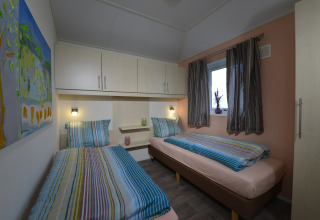 Dos camas individuales con ropa de cama a rayas en una acogedora habitación de Calcelux, Camping Brilon.