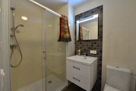 Baño moderno en la cabaña Calcelux con ducha, inodoro y lavabo en Camping & Ferienpark Brilon, Alemania.