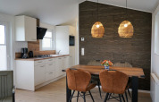 Cocina y comedor modernos en Chalet Alme, Camping & Ferienpark Brilon, con pared de madera y lámparas.
