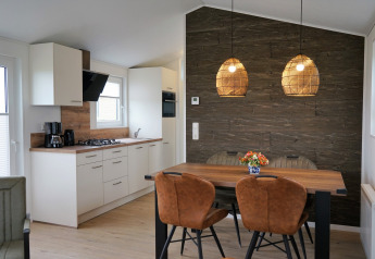 Moderna cucina e sala da pranzo nel Chalet Alme, Camping & Ferienpark Brilon, parete in legno e lampade.