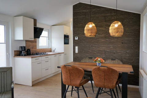 Modernes Chalet-Alme-Küchen- und Essbereich im Camping & Ferienpark Brilon mit Holzdekor und Lampen.