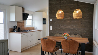 Cocina y comedor modernos en Chalet Alme, Camping & Ferienpark Brilon, con pared de madera y lámparas.