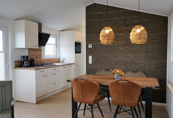 Modernes Chalet-Alme-Küchen- und Essbereich im Camping & Ferienpark Brilon mit Holzdekor und Lampen.