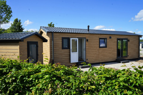 Buitenaanzicht van Chalet Alme, moderne houten cabin op Camping & Ferienpark Brilon in Duitsland bij zonnig weer