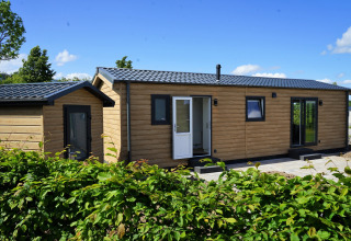 Buitenaanzicht van Chalet Alme, moderne houten cabin op Camping & Ferienpark Brilon in Duitsland bij zonnig weer