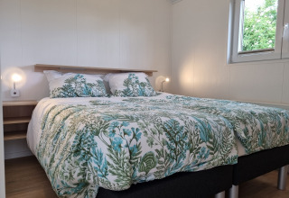 Schlafzimmer im Chalet Alme mit Doppelbett, botanischer Bettwäsche und Fenster im Ferienpark Brilon.