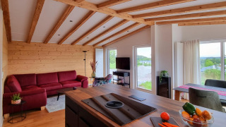 Interni di chalet moderni con travi in legno, divano rosso e grandi finestre, a Brilon, Germania.