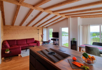 Modernes Chalet-Interieur mit Holzbalkendecke, rotem Sofa und weitem Ausblick, Brilon, Deutschland.