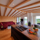 Interni di chalet moderni con travi in legno, divano rosso e grandi finestre, a Brilon, Germania.