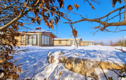 Chalet Enzian en Camping & Ferienpark Brilon, Alemania, rodeado de nieve y ramas secas bajo un cielo azul claro.