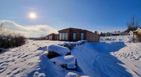 Día soleado de invierno en Chalet Enzian, Camping & Ferienpark Brilon, Alemania, con cabañas en la nieve.